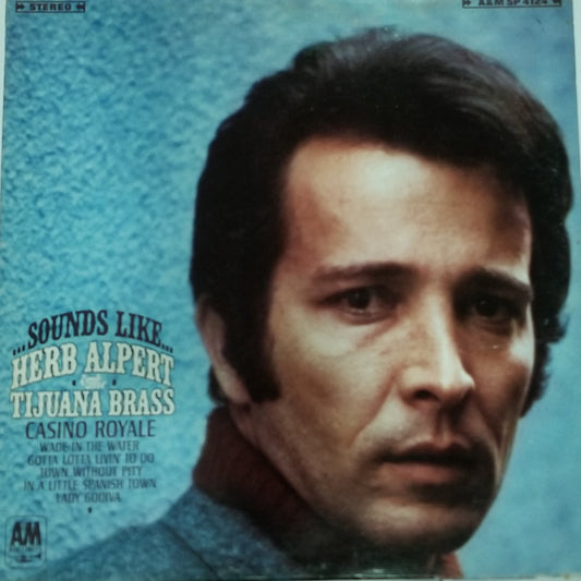 Album cover with a person's face and text about Herb Alpert and Tijuana Brass on a blue textured background